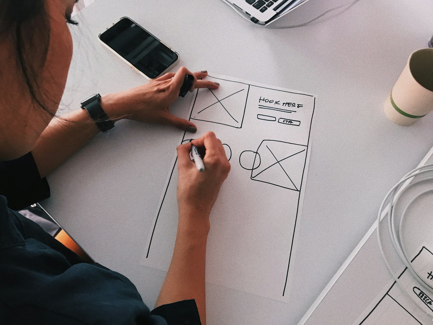 Designer che disegna un wireframe di sito web con etichette sulla scrivania.