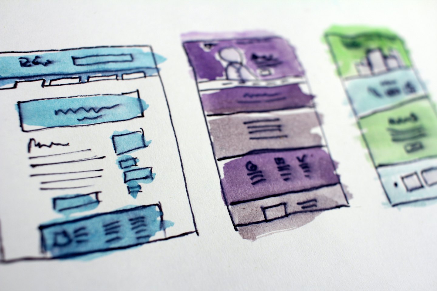 Tre schizzi wireframe acquerellati di layout di siti web.