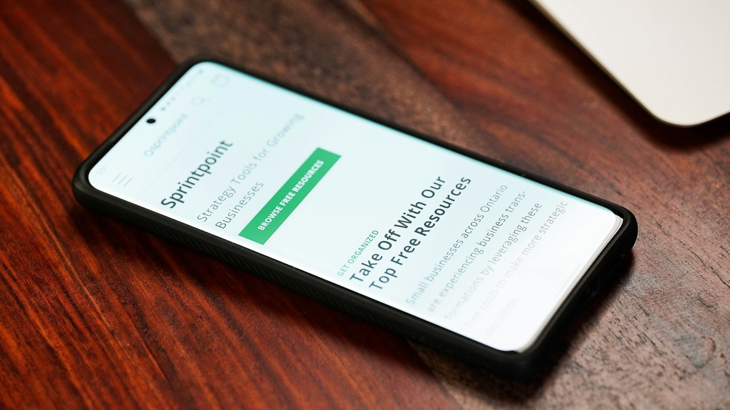 Smartphone con il sito web aziendale Sprintpoint su un tavolo di legno.